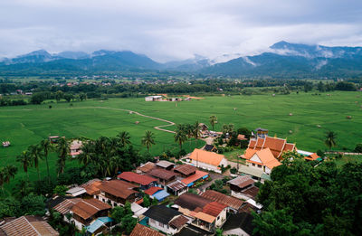 High angle view of houses on field by mountains against sky
