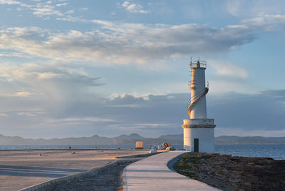 Lighthouse amidst sea and buildings against sky