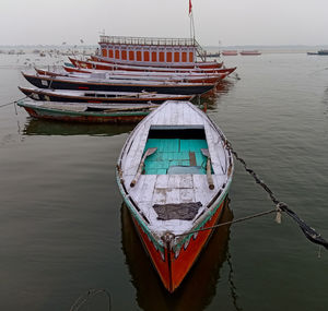 Fishing boat moored in sea against sky