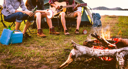 Low section of friends playing musical instruments at camp