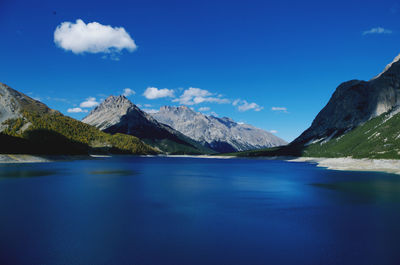 Scenic view of lake and mountains against blue sky