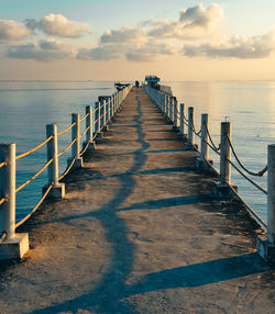 Pier over sea against sky during sunset