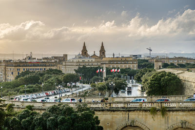 View of trees and buildings against cloudy sky