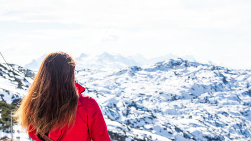 Rear view of woman standing on snow covered mountain