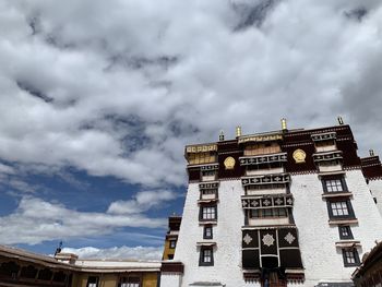 Low angle view of buildings against cloudy sky