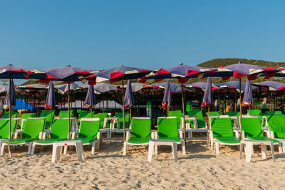 Chairs on beach against clear blue sky