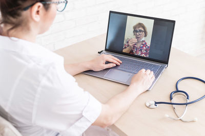 Midsection of doctor talking on video call at clinic