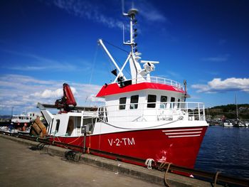 Boat moored at harbor against blue sky