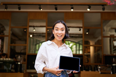 Portrait of young woman using mobile phone while standing in gym