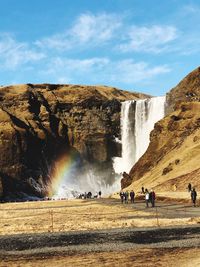 People enjoying at waterfall against sky