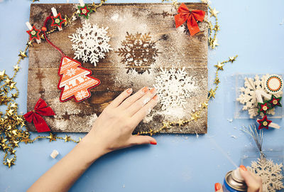 Cropped hands of woman spraying on snowflake during christmas 
