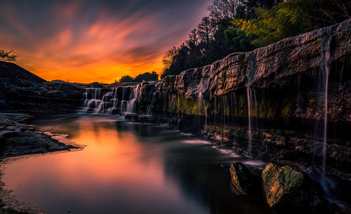 Scenic view of waterfall against sky during sunset