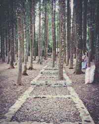 Rear view of woman walking on footpath amidst trees in forest