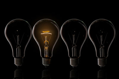 Close-up of illuminated light bulb against black background