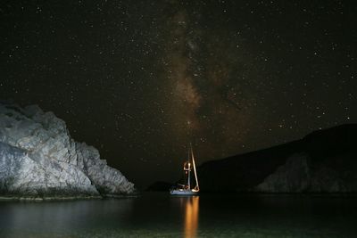 Illuminated sailboat sailing on sea against star field