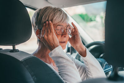 Senior woman wearing eyeglasses sitting in car