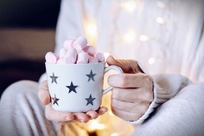 Midsection of woman holding cup filled with marshmallows