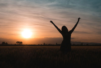 Silhouette person on field against sky during sunset