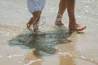 Low section of people splashing water at beach