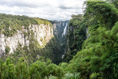 Scenic view of waterfall in forest against sky