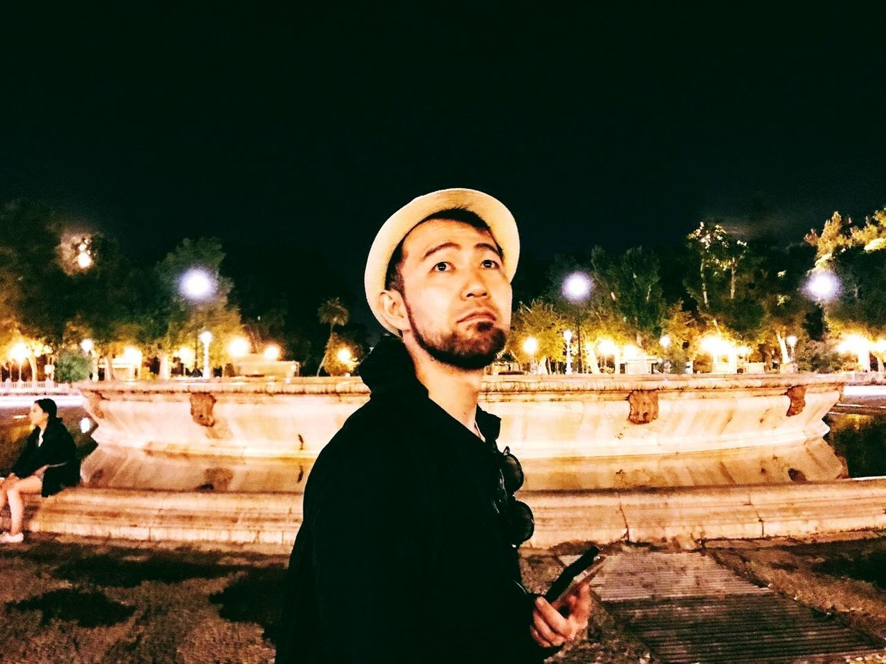 PORTRAIT OF YOUNG MAN LOOKING AWAY IN CITY AT NIGHT