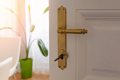 Close-up of handle of half- open vintage door in the room full of light 