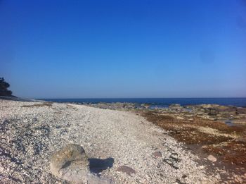 Scenic view of beach against clear blue sky