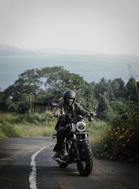 Rear view of man riding motorcycle on road