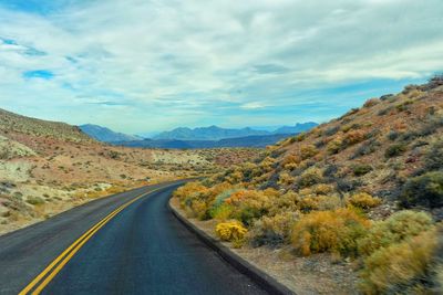 Road leading towards mountains against sky