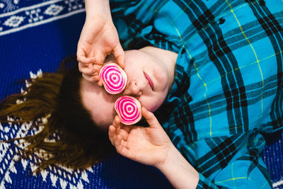 Close-up of woman holding food while lying on bed at home