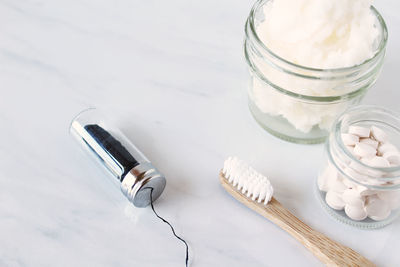 High angle view of toothbrush with toothpaste and medicines on white background