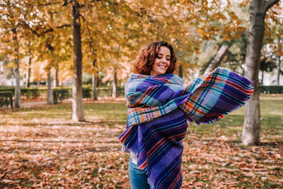 Portrait of a smiling young woman in autumn leaves