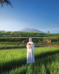 Woman standing on field against sky