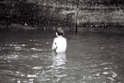 Rear view of boy swimming in water