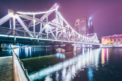 Illuminated bridge over river at night