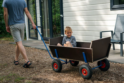 A man pulling a wooden wagon with his son.
