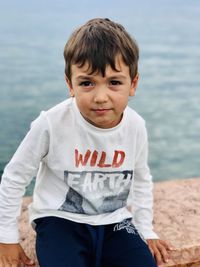 Portrait of boy sitting by sea