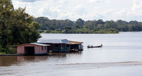 House by lake and buildings against sky