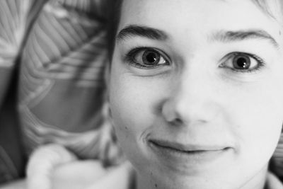 Close-up portrait of young woman smiling while lying on bed