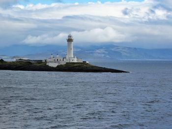 Lighthouse by sea against sky