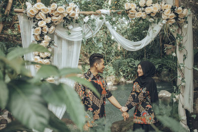 Couple with holding hands standing against decoration