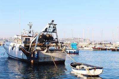 Boats moored at harbor against clear sky
