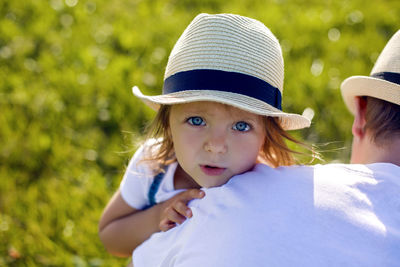 Little girl in the haystack in a hat and denim overalls