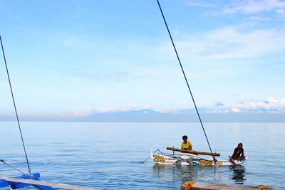 People sitting on boat in sea against sky