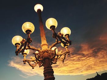 Low angle view of illuminated lighting equipment against sky