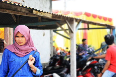 Young woman wearing hijab while looking away on street