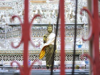 Buddha sculpture seen through railing