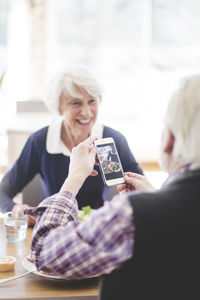 Woman using mobile phone while sitting on table