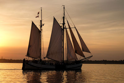 Sailboat sailing on sea against sky during sunset