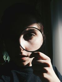 Close-up of woman looking through magnifying glass